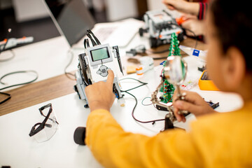 Cute little boy programming electric toys and robots at robotics classroom