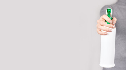 Hand with spray bottle on grey background.