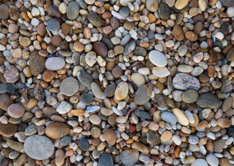 Close up of round, smooth pebbles on beach. Natural background texture.