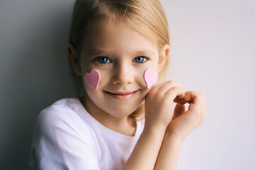 Pretty blonde girl show heart shape symbol with hands. Child and valentines day. Love. Pink hearts on a face. - 403066898