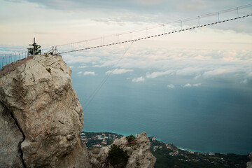 travel in the mountains, dangerous suspension bridge cable car between two rocks. Beautiful background view of the sea and blue sky.