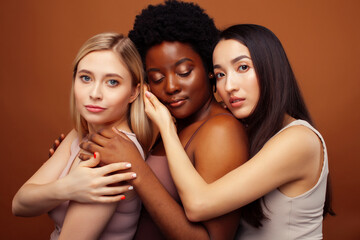 young pretty asian, caucasian, afro woman posing cheerful together on brown background, lifestyle diverse nationality people concept