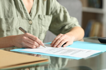 Woman hands signing contract on a glass table at home