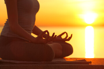 Woman silhouette doing yoga exercise at sunset