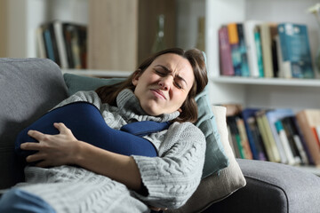 Woman suffering ache with broken arm in a sling at home
