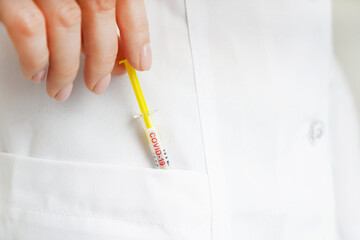 Covid-19 vaccine concept with a syringe marked covid-19 taking from a doctor pocket