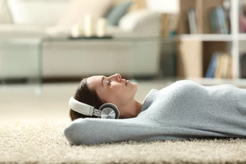 Tuinposter Relaxed woman listening to music with headphones at home © PheelingsMedia