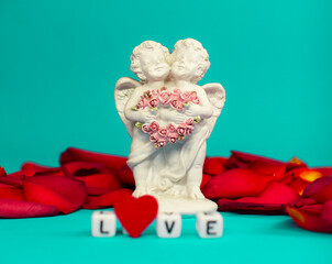 Two cute angels and the word love on the background of rose petals .Valentine's Day. Postcard for the holidays