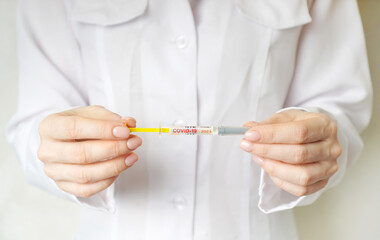 Covid-19 vaccine concept with a syringe marked covid-19 in a doctor hands