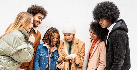 Fashionable multiethnic friends having fun together outdoors, looking at mobile phone.