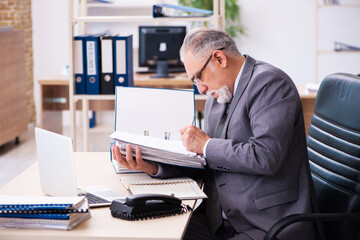 Old male employee and paperwork in the office