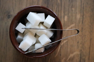 white sugar cubes in a bowl on a wooden table in cafe