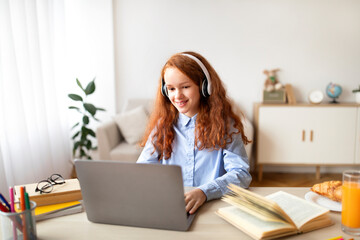 Girl wearing headphones using laptop looking at computer