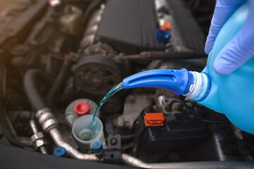 Pouring windshield washer fluid, frost guard concentrate from plastic bottle into car washer fluid...