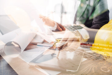 Two colleagues discussing data working and tablet, laptop with on on architectural project at construction site at desk in office