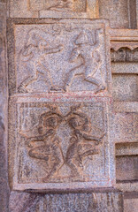 Hampi, Karnataka, India - November 4, 2013: Hazara Rama Temple. Closeup of double brown stone pillar sculptures of dancing women and Hayagriva dancing with monkey, maybe Hanuman.