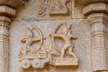 Hampi, Karnataka, India - November 4, 2013: Hazara Rama Temple. Closeup of beige stone damaged sculpture on wall featuring archer battle scene.