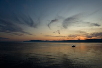 Naklejka premium Sunset on Baikal lake with sun setting down behind the mountain and sun rays