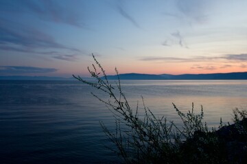 Sunset on Baikal lake with sun setting down behind the mountain and sun rays