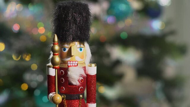 Wooden Nutcracker doll in front of sparkling Christmas tree