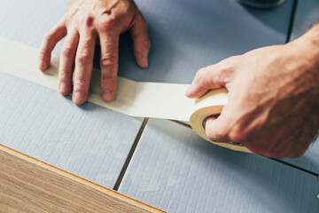 Bonding sheets of thermal insulation and sound insulation with adhesive tape before laying the...