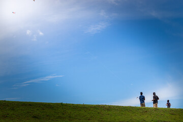 Obraz na płótnie Canvas Two boys flying kites in a grassland mountain hill, blue bright sky scenic landscape,