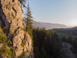 The rocky mountain with trees at clean blue sky background. Beautiful landscape with hills, river and forest. View from drone. Travel journal image. Wallpaper design.