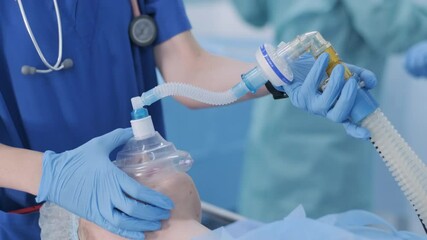 The anesthesiologist, in medical gloves, prepares female patient for surgery, puts her into anesthesia, regulates oxygen mask. surgery. anesthesia