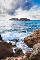 Fototapeta na wymiar Waves crashing against the rocks in coastal landscape. Malgrats Islands in Mallorca. Tourism in the Mediterranean. 