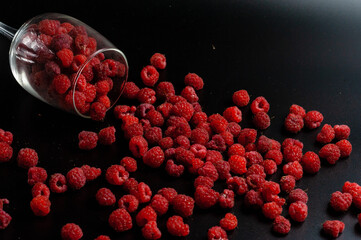 raspberries in a glass on a black background