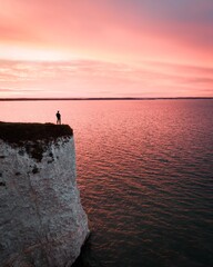 a traveler standing on a remote rock in front of the sea in a dreamy scenery while sunset