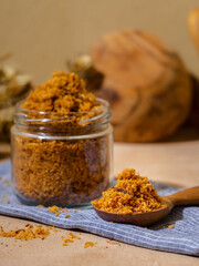 shredded chicken served in a glass jar and wooden spoon.