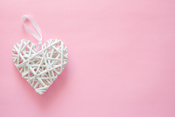 Wicker white heart on pink background. Valentine's day and love romantic concept with copy space for text.