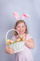 Happy cute girl with bunny ears. Easter greeting card background. with Easter eggs and spring flower in basket