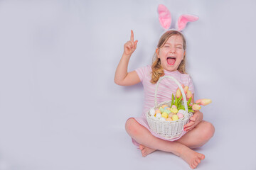 Happy cute girl with bunny ears. Easter greeting card background. with Easter eggs and spring flower in basket