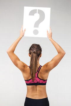 fit girl in sportswear holding question mark sign