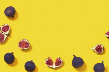 Fresh figs whole and sliced figs on yellow paper surface with copy space. Food background.