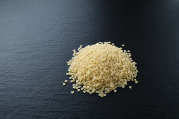 Raw pasta stars, on a black textured stone table, side view.