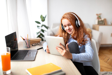 Girl wearing headphones enjoying podcast using tablet - Powered by Adobe