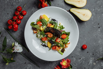 Traditional shrimp and mango salad in a restaurant. Fried shrimp salad with rosemary, mango, cherry tomatoes, salad mix, mango chili sauce.