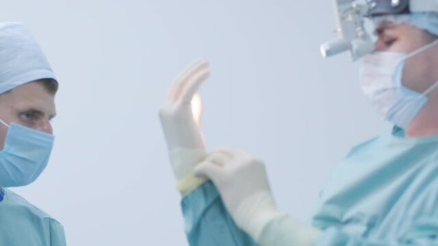 Nurse helping the surgeon to put on sterile gloves before surgery
