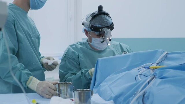 Operation to remove tonsils. In modern clinic under deep anesthesia, using latest devices patient removes glands, cold plasma method, cuts swelling in throat, doctor works with new probe