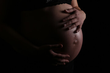 Pregnant woman caressing her belly low-key