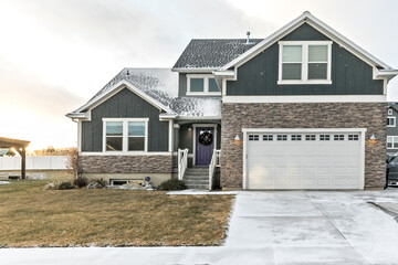 A modern dark gray and white new construction craftsman with stone accents and a purple front door in Salt Lake city on a snowy winter December day