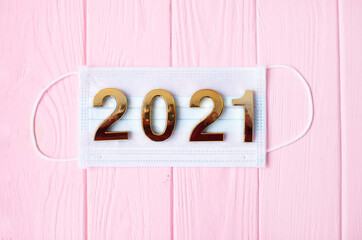 2021 with a protective face mask. face mask for covid-19 coronavirus on pink background.
