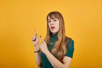 Obraz premium Hand points index finger up, pointing forefinger surprise gift option, great idea. Young attractive woman, dressed green shirt blonde hair, yellow background