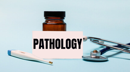 On a blue background - a bottle for pills, a stethoscope, an electronic thermometer and a card with the inscription PATHOLOGY. Medical concept