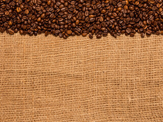 brown roasted coffee beans on burlap sack background