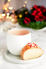 Obraz na płótnie Canvas Christmas scene. Piece of Kings cake with an empty white ceramic cup. In the background Christmas lights and mistletoe