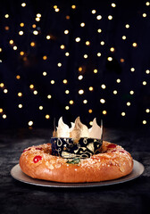 .Christmas scene..Three Kings cake with candied fruit and almonds on a gray plate. With a crown on...